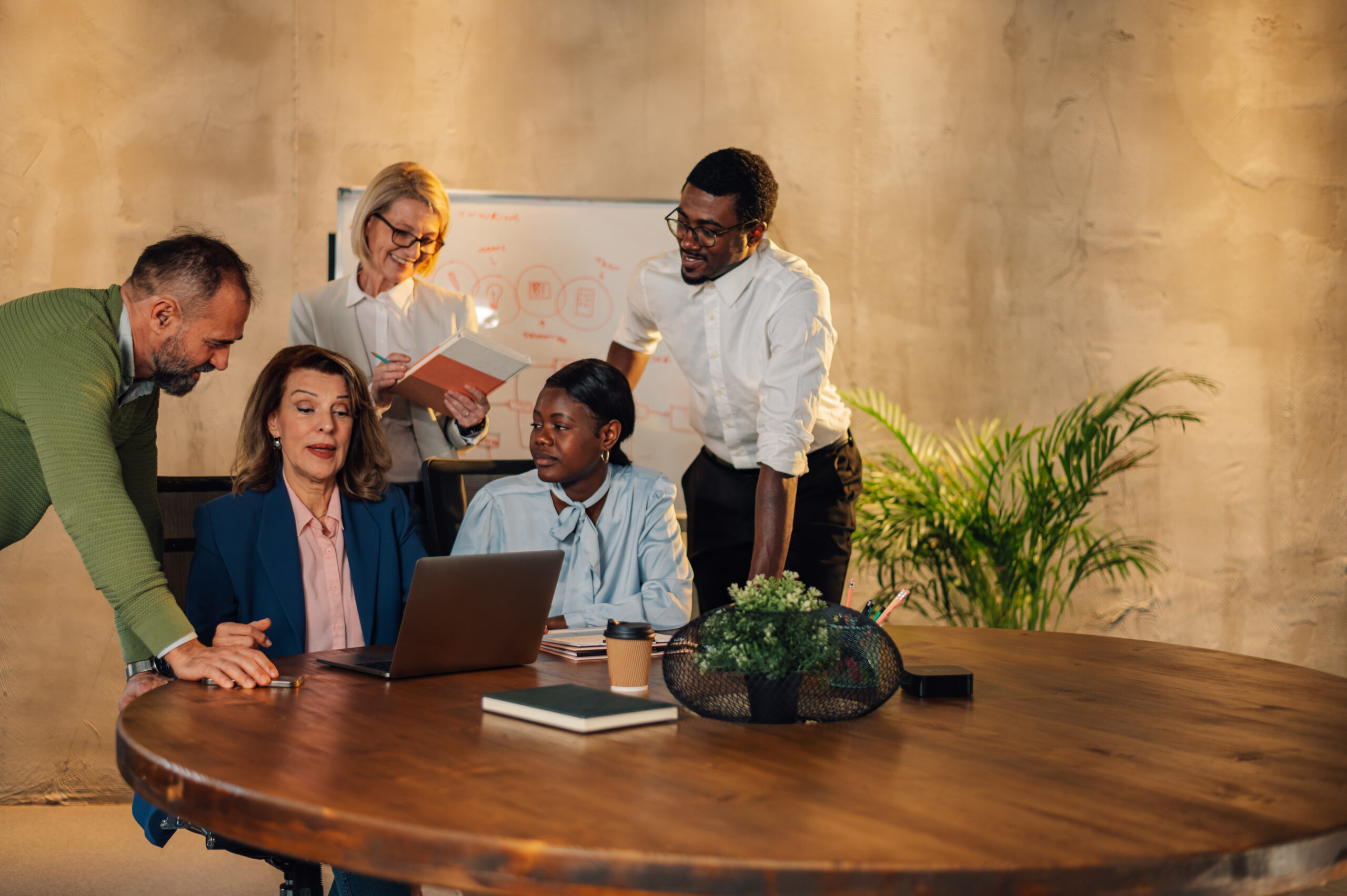 Group of multiracial colleagues talking about company projects during a meeting in a boardroom. Teamwork concept. Diverse coworkers working together.